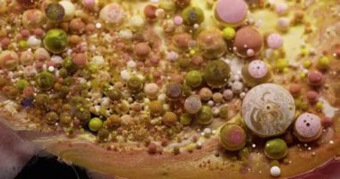 Yağlı boya. Köpüklü sıvı. Renkli sıvı karıştırıcı köpük patlıyor. Sarı altın rengi bilye dökülüyor soyut arkaplan parıldıyor.