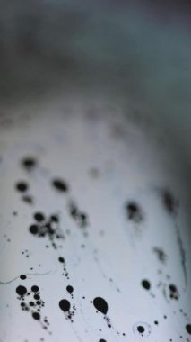 Dikey video. Köpük akışı. Köpük sıvısı. Odaklanmamış mavi renk köpüklü doku, koyu siyah ışık parlaması üzerinde sıvı karışımı dalga hareketi soyut sanat arkaplanı.