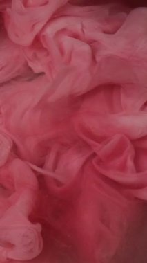 Dikey video. Mürekkep damlası. Duman bulutu. Odaklanmamış kırmızı pembe renkte parıldayan parıldayan parıltı su altı patlaması kabarcığı soyut sanat arkaplanı gibi hareket ettiğini gösteriyor..