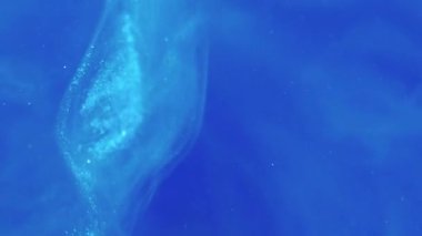 Işıl ışıl. Boya karıştırıyorum. Odaklanmamış parlak mavi sıçramalı mürekkep buharı girdabı duman bulutu sıvısı soyut sanat modern arka planda ilerliyor.