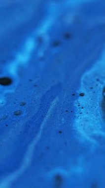 Dikey video. Boya baloncukları. Yumuşak sıvı doku. Odaklanmamış mavi renk ışıldayan parçacıklar emülsiyon karışımı dökülme hareketi soyut sanat arkaplanı.