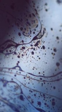 Dikey video. Fizzy sıvısı. Kabarcık boyası. Odaklanmamış mavi sarı renk yağ dokusu koyu soyut sanat arka planında benzinli sıvı karıştırma hareketi.