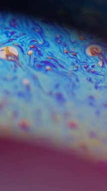 Dikey video. Odaklanamayan kimyasal kabarcıklar. Boya köpüğü. Sarı mavi pembe renk gradyan asit sıvısı harmanlama hareketi soyut sanat arkaplanı.