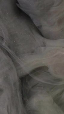 Dikey video. Parlak duman dokusu. Duman külü. Odaklanmamış gri renkli, ışıl ışıl parçacıklar yüzen boya suyu sıçrama hareketi karanlık soyut sanat arkaplanı.