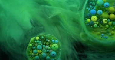 Yeşil sıvı. Kabarcık boyası. Şeffaf yağ çemberleri mermer üzerinde yüzen renkli köpük mürekkebi düşürür. Odaklanamayan su soyut arka plan yüzeyini titretir..