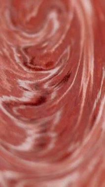 Dikey video. Mermer sıvısı. Boya dökülmüş. Odaklanmamış kırmızı beyaz renk parıldayan doku emülsiyon akış dalgası hareketini soyut sanat arka planı harmanla.