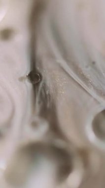 Dikey video. Yağ sıvısı. Pırıltılı sis. Odaklanmamış beyaz bronz bej rengi şeffaf köpükler yüzen mürekkep akışı hareketi soyut sanat arka planı.