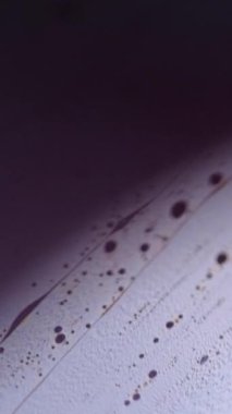 Dikey video. Bulanık köpük akıyor. Köpük sıvısı. Odaklanmamış mor renkli köpüklü desen, koyu siyah ışık parlaması üzerinde sıvı dalgası, soyut sanat arkaplanı.