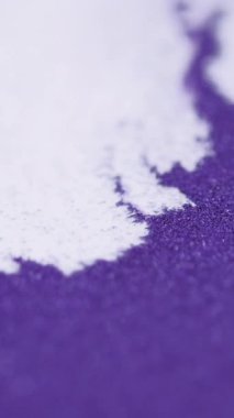 Dikey video. Parıltılı boya döküldü. Parçacık dokusu. Odaklanmamış beyaz mor renk parıldayan sıvı leke dalgası ışık saçar soyut sanat arkaplanı.