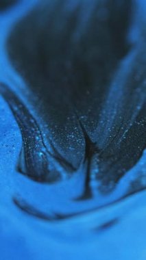 Dikey video. Mürekkep karışımı. Parıldayan sıvı dökülmesi. Odaklanmamış siyah mavi renk parıldayan parçacıklar dokusu akrilik dalga hareketi soyut sanat arkaplanı.