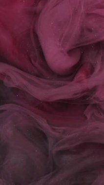 Dikey video. Duman girdabı. Boya suyu karışımı. Odaklanmamış pembe renkli toz parçacıkları koyu soyut sanat arka planında sis dalgası hareketi.