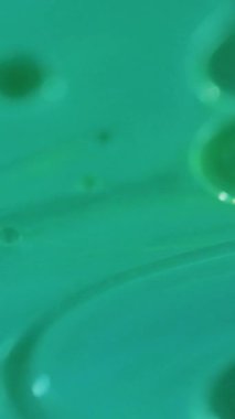 Dikey video. Yağ kabarcıkları. Köpüklü sıvı. Odaklanmamış yeşil renk şeffaf yuvarlak damlacıklar yüzen jel dokusu boya su akışı hareket soyut sanat arka planı.