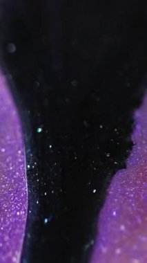 Dikey video. Mürekkep damlası. Parıldayan sıvı dökülmüş. Odaklanmamış siyah mor renk parıldayan doku cilası akış hareketi soyut sanat arkaplanı bokeh ışık.