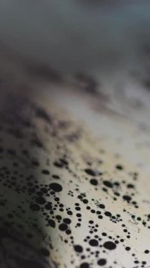 Dikey video. Bulanık köpük dokusu. Mürekkep akışı. Odaklanamayan siyah sarı renkli köpüklü yağlı kimyasal emülsiyon dalgası soyut sanat arka planı.