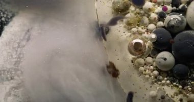 Çok renkli sıvı. Kabarcık boyası. Işıldayan gümüş akışı pürüzsüz boya köpüklü yağ damlalarını karıştırıyor. Soyut parçacıklar su arkaplanı.