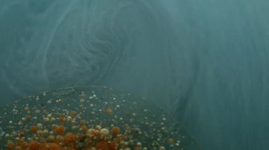 Sis sarmalı. Yağ damlası akışı. Mavi gri mermer akarsu etrafında dönüyor. Soyut duman arka planında turuncu bej mürekkep topları..