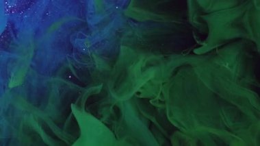 Sıvı sıçraması. Mürekkep dumanı. Odaklanamayan yeşil, çok renkli parıldayan boya deseni sisi parıldayan soyut sanat arka planında yüzüyor..