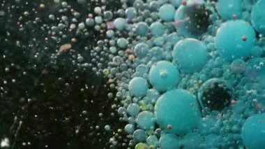 Fizzy sıvısı. Pigment damlası. Mavi, siyah, köpüklü, mürekkepli su akışı. Patlayan yağ parçacıkları renk damlaları soyut arkaplanı bulanıklaştırır.