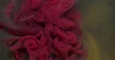 Parıltı sıçraması. Mürekkebi karıştır. Bulanık pembe, mor, sarı renkli su soyut karanlık sanat arka planında süzülen parlak parçacıklar..