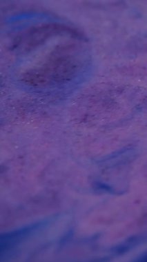 Dikey video. Akrilik sıvı. Boya sızıntısı. Mor mavi, diş mineli, ışıltılı sıvı karışımı. Doku bozulması değişken yüzey mermer etkisi.