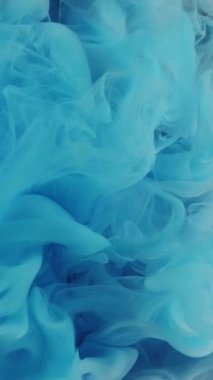 Dikey video. Su damlasını boya. Duman bulutu. Mavi pembe mürekkep, sisli havada süzülen dalgalar, siyah soyut arka planda devinimi gösteriyor..