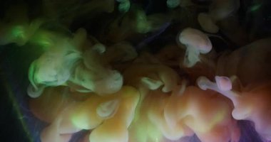 Bulut mürekkebi. Parıldayan sis. Parlak duman patlaması siyah arkaplanda renk pigmentini karıştırıyor. Sarı yeşil soyut parıltı sihirli akışı.