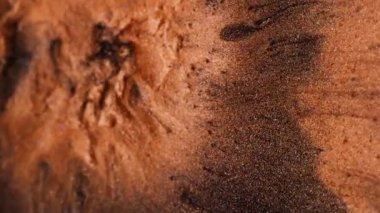 Dikey video. Mürekkep döküldü. Parıldayan patlama. Turuncu lav püskürmesi volkanı. Erimiş bakır kütle karışımı siyah sıvı soyut arkaplan boyunca.