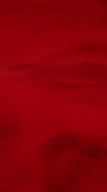 Dikey video. Kırmızı dalga. Boya sıvısı. Parlak diş minesinin mermer dokusunda parıltı tozu var. Kan akışı sanatsal arka planına akrilik farklı renkler dökülüyor.