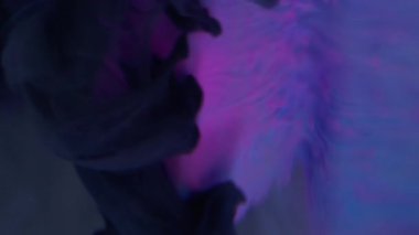 Dikey video. Sanat dumanı. Grunge dumanı. Mistik siyah suluboya çözünmüş mürekkep dökülmüş pembe mor elmas figürünün üzerine dökülüyor soyut menekşe arkaplan.