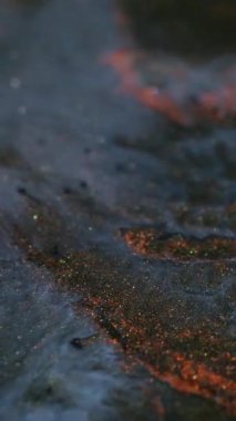 Dikey video. Işıl ışıl lav. Difüzyon boyası. Metalik simli parlak opak kütle. Siyah sanat jeli bakır parçacıkları sıvı girdap volkanik kum etkisi ile akıyor.