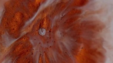Dikey video. Parıltı patlaması. Boya çiçeği. Turuncu bakır metal toz sıvısı beyaz diş minesi sıvı yüzeyine yayılmış. Yuvarlak lekeler, soyut sanat geçmişi..