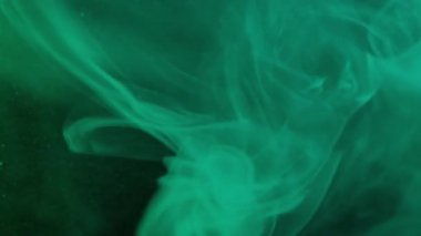 Renk buharı. Duman girdabı. Parlayan yeşil turkuaz peçe mürekkep spreyi çözülmüş karışım parıldayan kum yüzeyi soyut su karışımı.