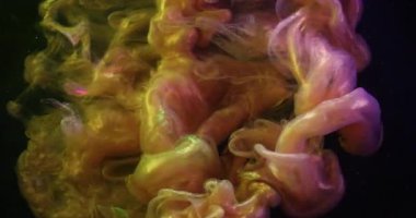 Pigment damlası suyu. Işıl ışıl. Pembe sarı mürekkep iğnesi sıvıda çözünüyor. Soyut bulanık siyah arkaplanda renkli buhar karışımı.