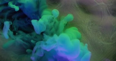 Duman patlaması. Boya akışı. Mor gri arka planda mavi yeşil sıvı sis dalgası spreyi. Renkli neon rengi soyut pigment karışımı bulanık üflemeli.