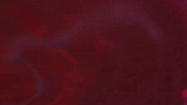 Odaklanamayan sıvı dökülmesi. Boya sıçraması. Bulanık neon pembe mor duman dokusu parlayan mürekkep akışı koyu soyut sanat arkaplanı.