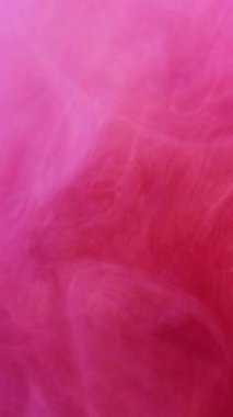 Dikey video. Soyut renk. Dönen mürekkep. Odaklanmamış parlak pembe mor boya bulutu duman buharı sanat arka planında hareket ediyor..