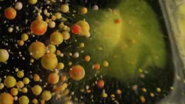 Mürekkep patlaması. Kabarcık patladı. Siyah suya dökülen renkli parçacıklar. Turuncu yağ pigmenti bulanık sıçrama soyut arkaplan patlaması.