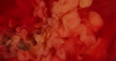 Duman patlaması. Duman boyası. Kırmızı köpüklü suya turuncu dalga pigmenti döküldü. Renk akışı çözünmüş boya soyut kıvrım arkaplanını çözer.