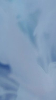 Dikey video. Su sıçraması. Sıvı damlası. Odaklanamayan mavi çok renkli parlak duman bulutu soyut ışık arka planında yüzen sıvı leke..