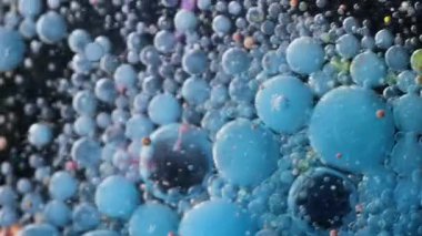 Fizzy sıvısı. Pigment damlası. Mavi, siyah, köpüklü, mürekkepli su akışı. Patlayan yağ parçacıkları renk damlaları soyut arkaplanı bulanıklaştırır.