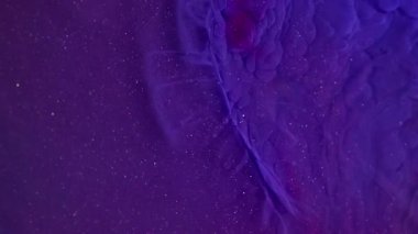 Işıldayan sıvı. Renkli akıntı. Mor mavi sıvı mürekkep karışımı bulut dokusu dalga yüzeyi. Hipnotik soyut arkaplan ışıldayan parçacıklar.