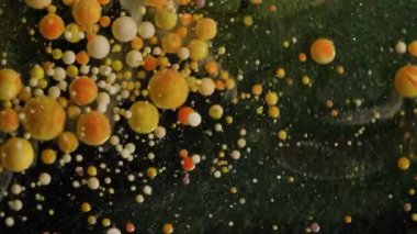 Boya damlası. Mürekkep çözülüyor. Yağlı boya damlaları koyu suda patlıyor. Sarı turuncu pigment tozu soyut sanat arkaplanı sıçratır.