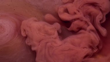 Dönen dokular. Soyut boya. Su parlaklığındaki pembemsi bronz mürekkep akrilik yaratıcı ıslak sanat üzerine sıçramış pigmentler..