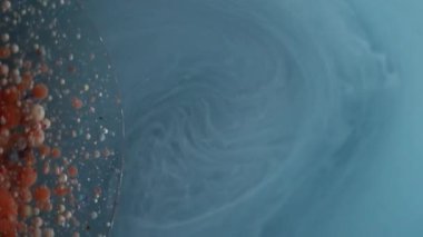 Sis sarmalı. Yağ damlası akışı. Mavi gri mermer akarsu etrafında dönüyor. Soyut duman arka planında turuncu bej mürekkep topları..