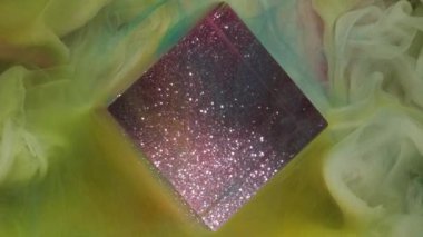 Buhar akışı. Parıltı küpü. Sarı yeşil renkli mürekkep suyu duman bulutu dokusu mor parıldayan geometrik kare şekilli soyut sanat arka planında yüzüyor.