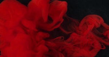 Renk buharı. Mürekkep atışı. Suyun altında kırmızı kıvrım pigmenti çözülür. Siyah arkaplan üzerine sisli sıvı parlak sprey. Odaklanamayan soyut akış.