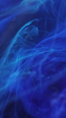 Dikey video. Parlayan buhar. Yüzen darbe. Odaklanmamış parlak mavi sıçrama boya lekesi sihirli duman soyut sanat arka planında hareket ediyor.