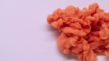 Mürekkep dalgası. Sigara arkaplanı. Odaklanmamış turuncu bronz renk su püskürtme parçacıkları beyaz sanatın ıslak soyutlamasına yayılıyor..