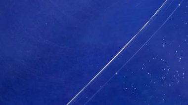 Yağ mürekkebi suyu. Yüzen boya. Boyayı küçük parçacıklarla renkli sıvıya düşürür. Sanat mavisi sıvı çözünmüş ışıltılı sis soyut arkaplan dokusu.