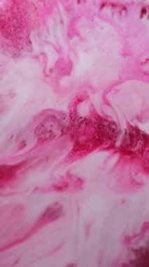 Dikey video. Renkli sıvı. Parıltı akışı. Beyaz pembe kırmızı karışımlı sıvı pigment dokusu girdaplı parlak metal cilası parçacıkları mürekkep soyut arkaplan bulanıklığı.